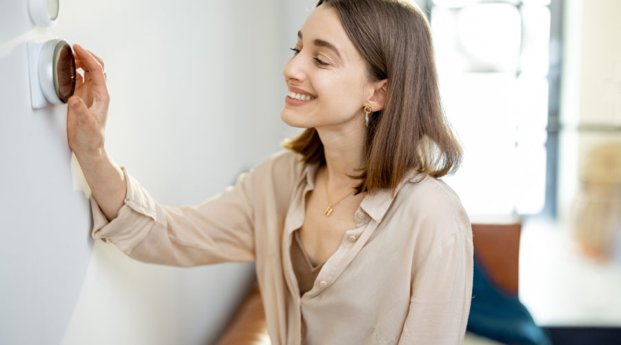 How To Heat Your Home Efficiently During the Cold Months 3 woman standing near the heat regulator at home 2021 09 01 12 16 26 utc