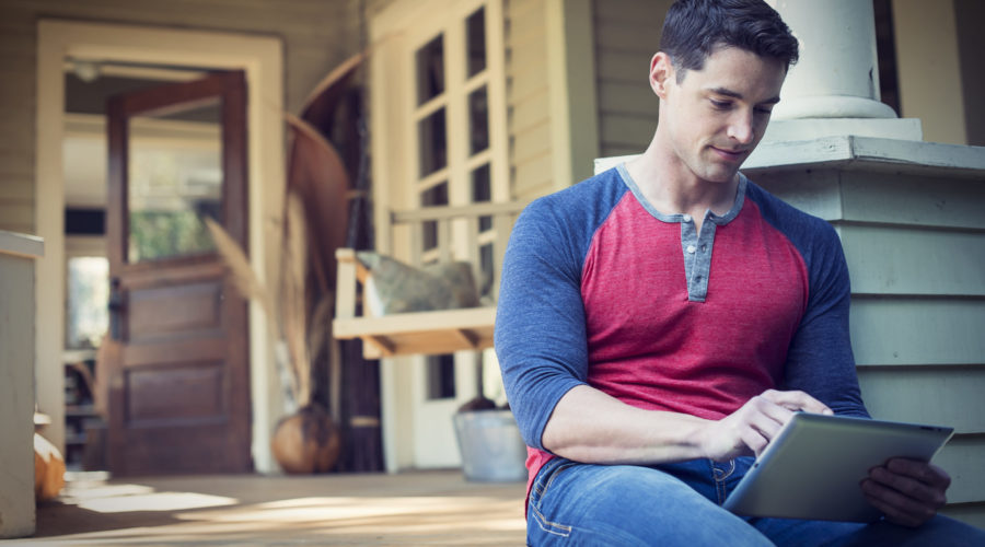 How To Enjoy a Day Out on Your Porch 4 A man sitting relaxing in a quiet corner of a porch, using a digital tablet.