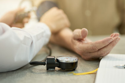 Professional doctor measuring heart-rate and blood pressure of aged person