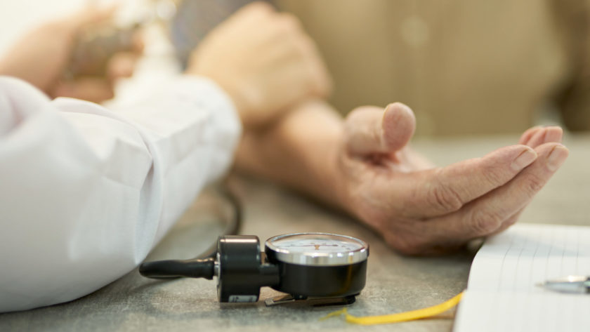 Professional doctor measuring heart-rate and blood pressure of aged person