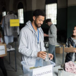 Volunteers working in community charity donation center., sorting out clothes and canned food.