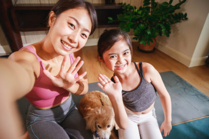 Asian woman yoga teacher and little girl filming yoga online class on video.