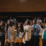 a group of middle school students stands on a stage, receiving accolades for their achievements in the honor society.